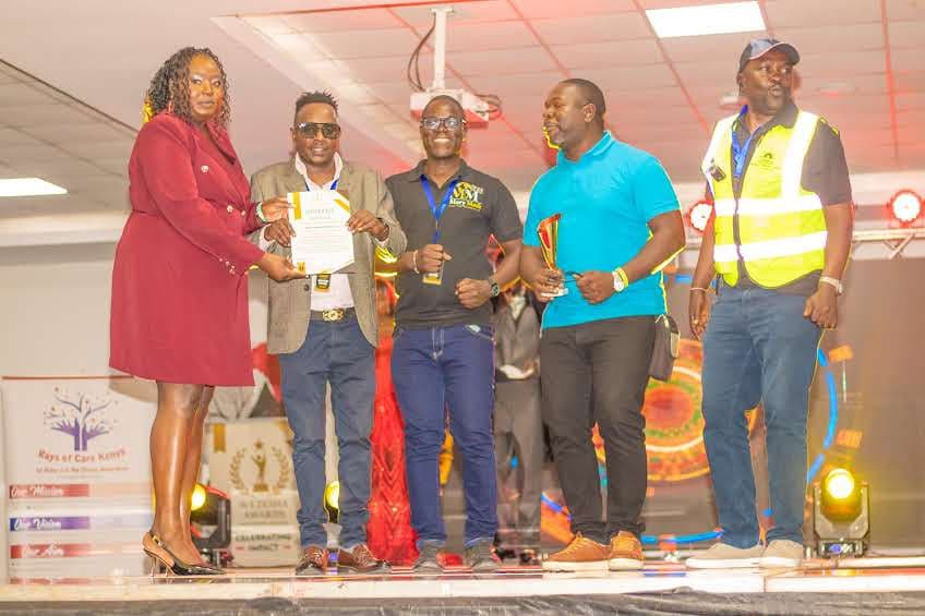 Winners holding certificates under the stage lights