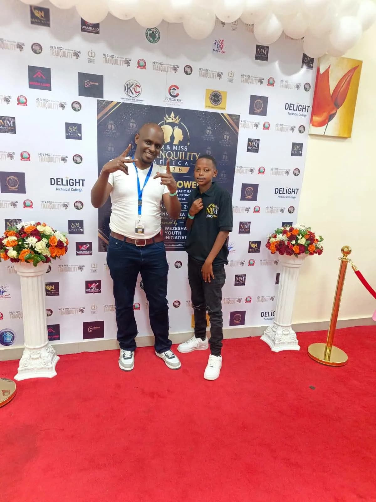 A guest and a young attendee posing at the sponsor backdrop